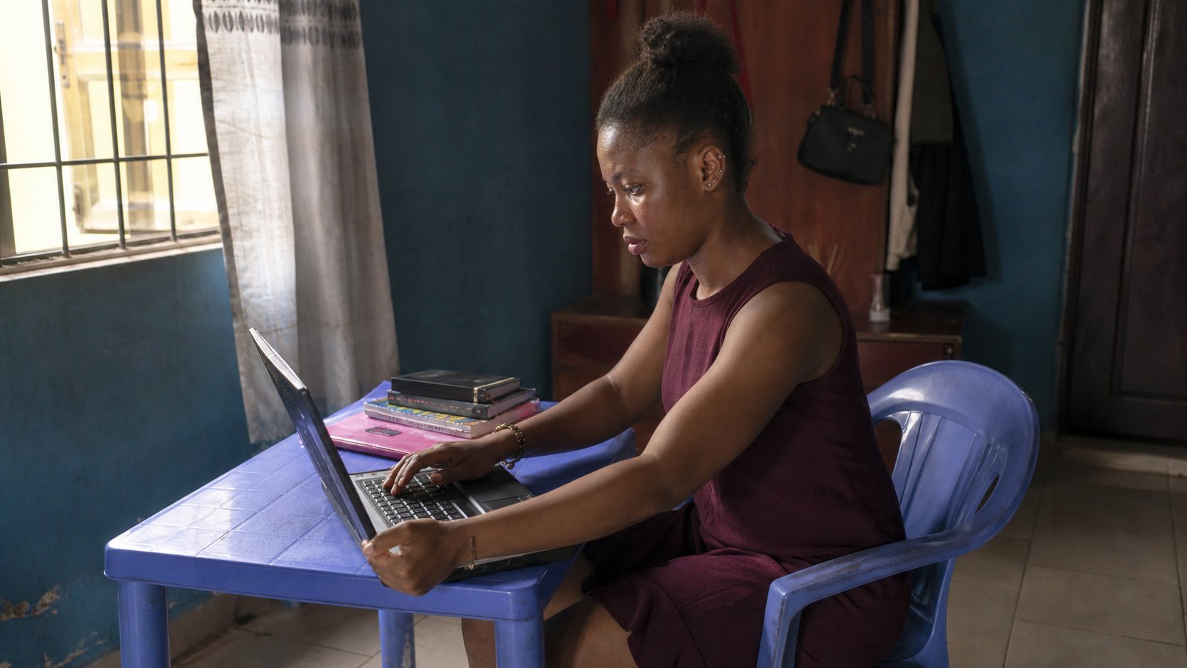 A young woman adjusting laptop brightness at a small table.
