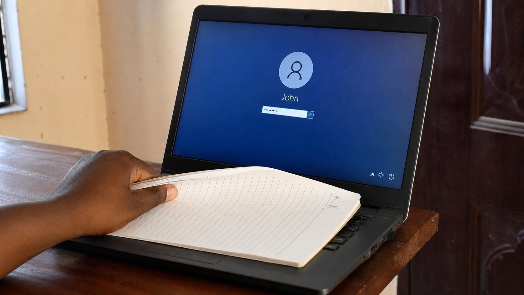 A notebook covering the keyboard while a password is typed, helper looking away.