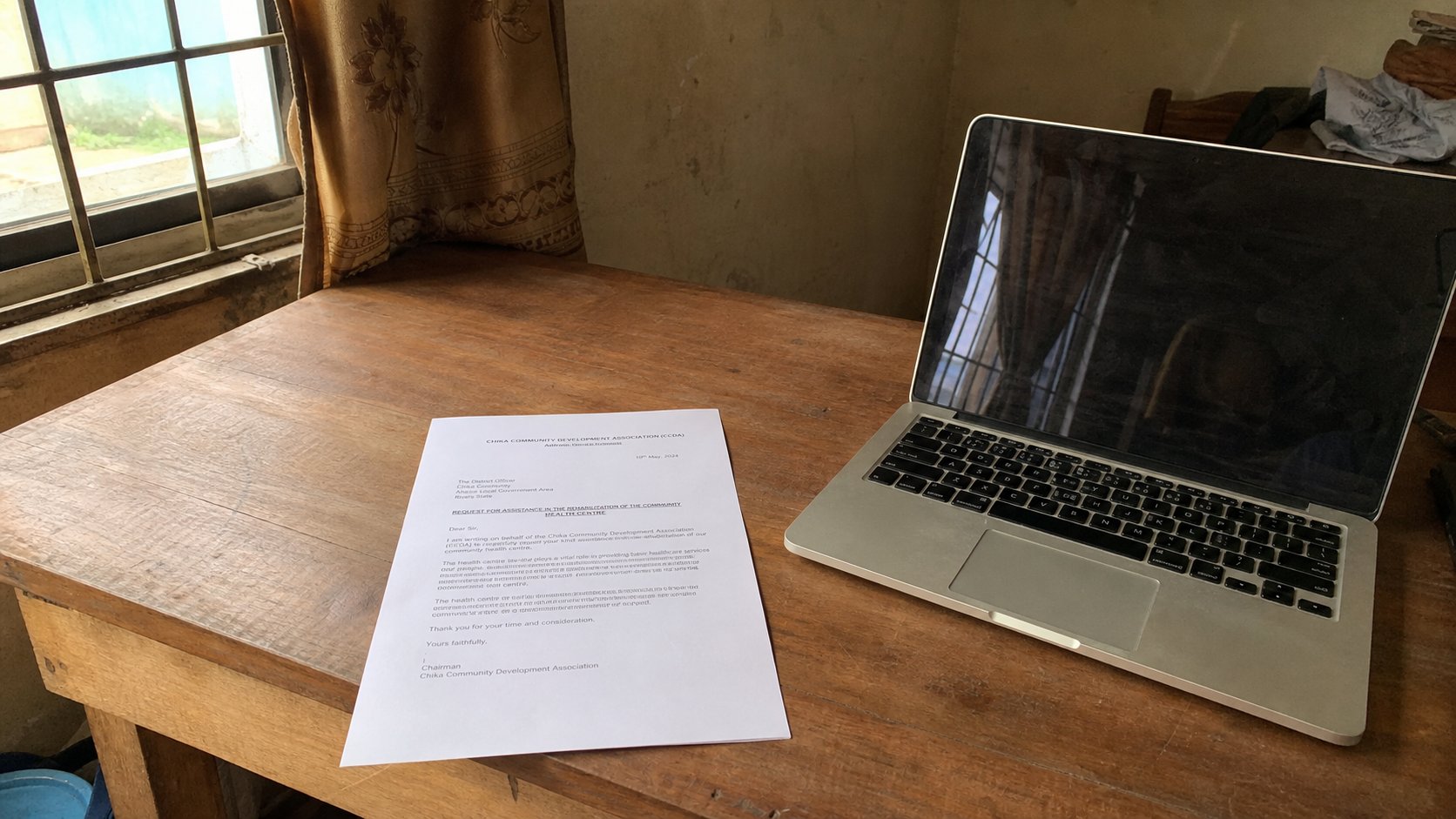 A printed letter with a simple header, beside a laptop.