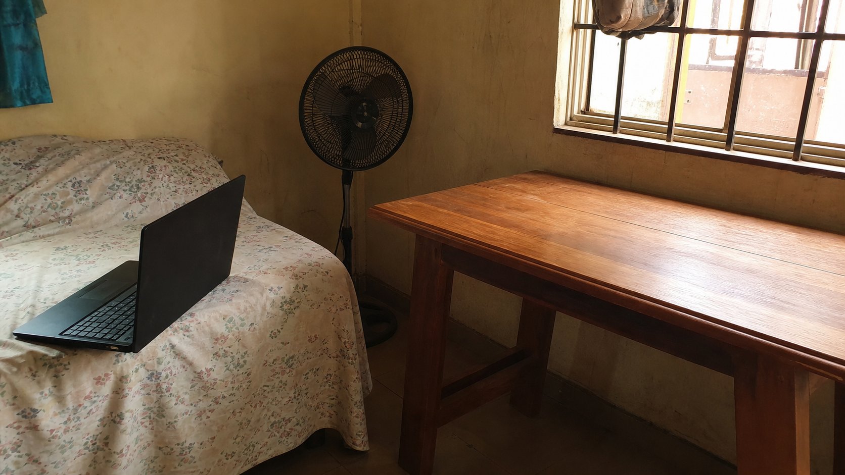 A laptop on a bedspread, with a clear table nearby.