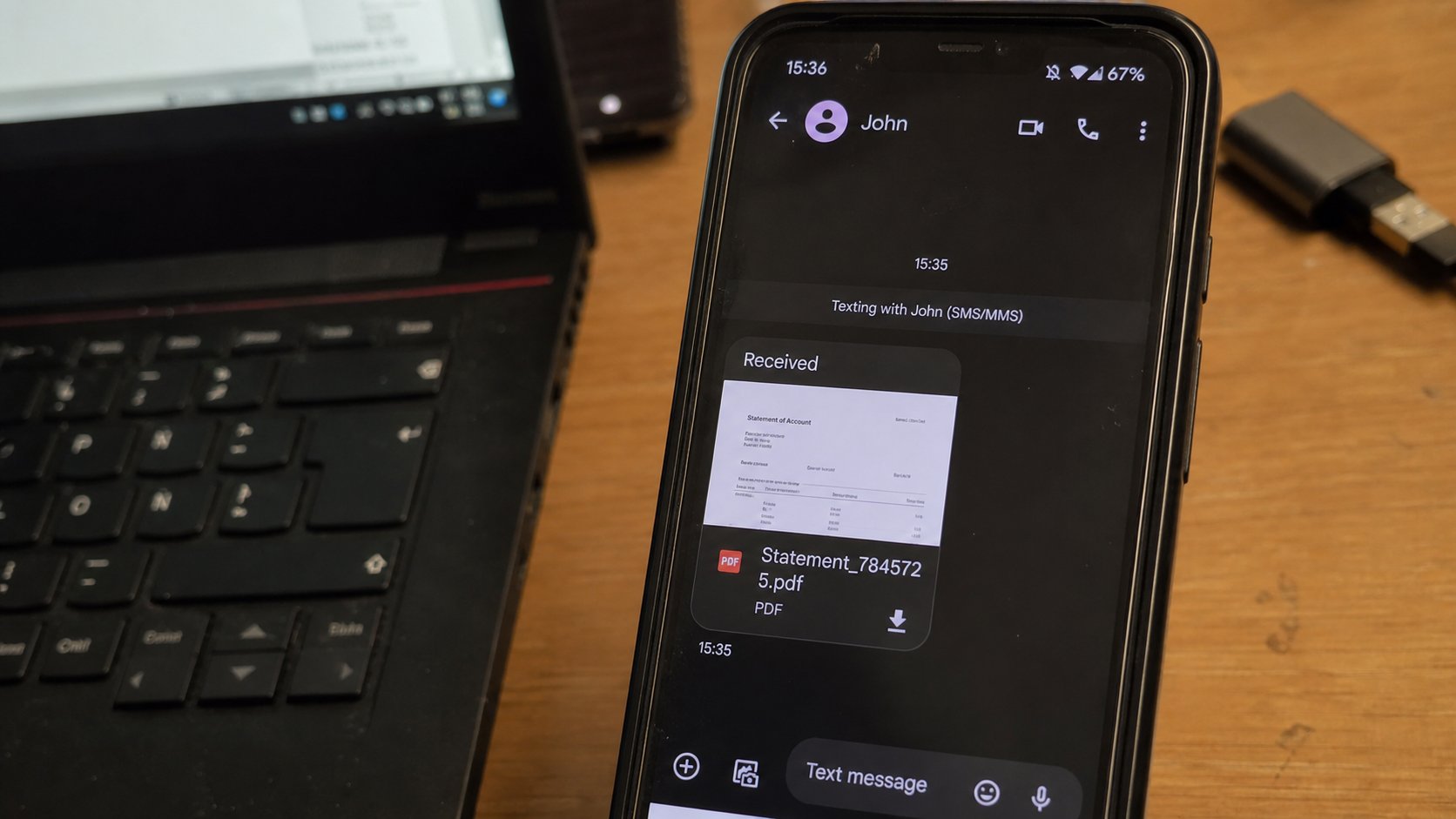A phone showing a received document, laptop beside it.