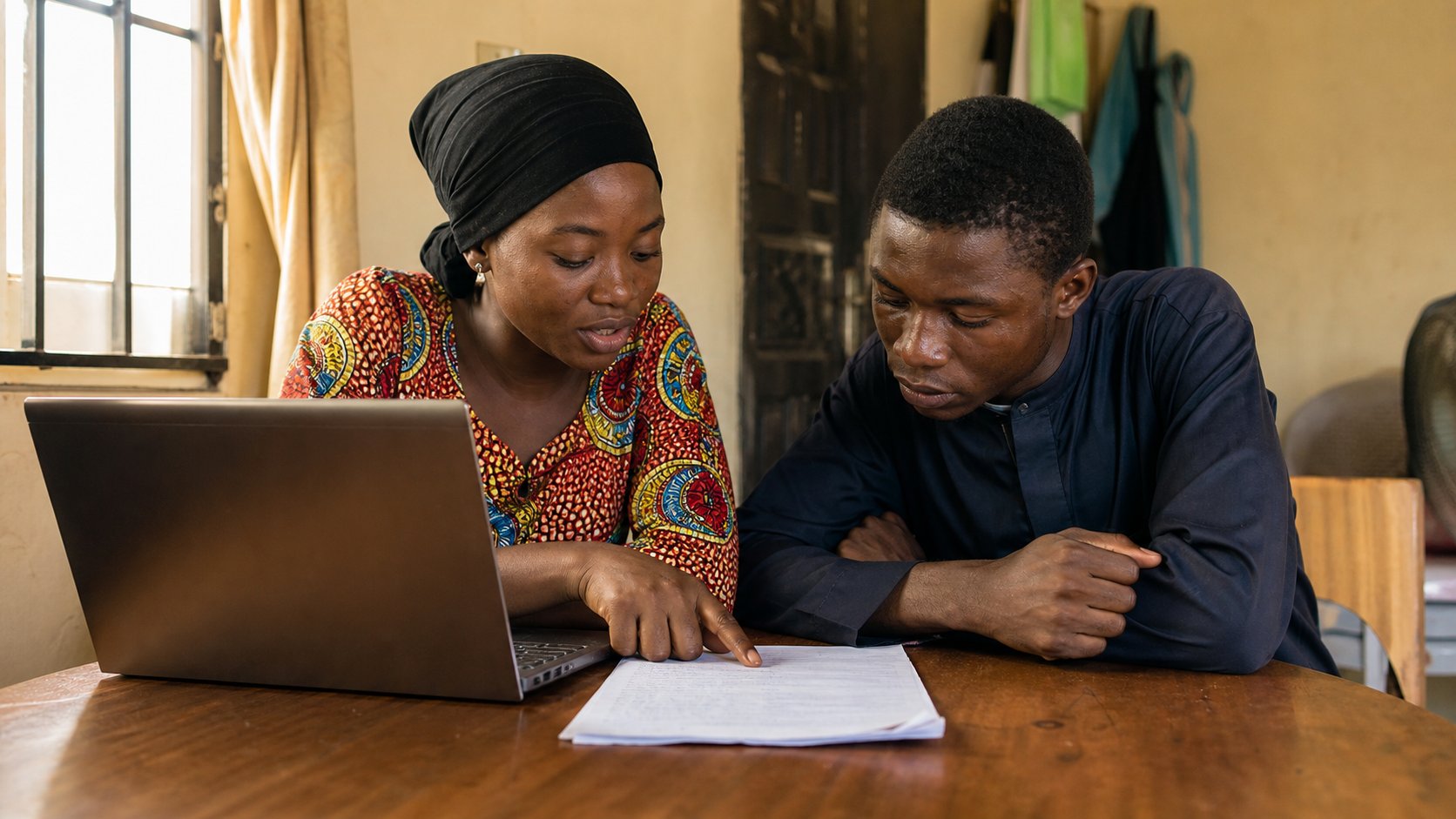 Two people looking at a commented document on one laptop.
